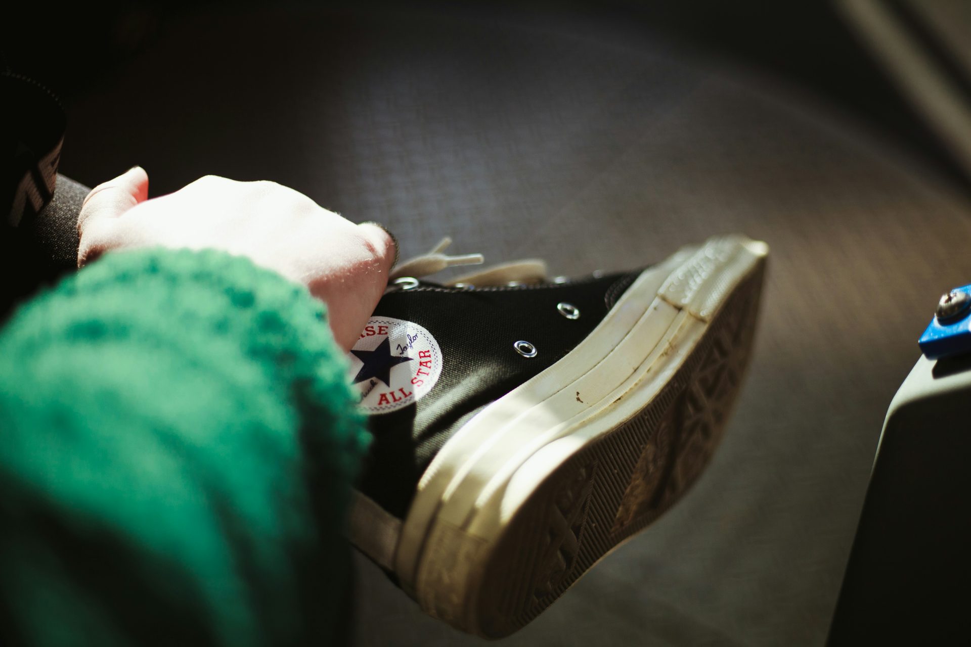 person holding black Converse All-Star shoe